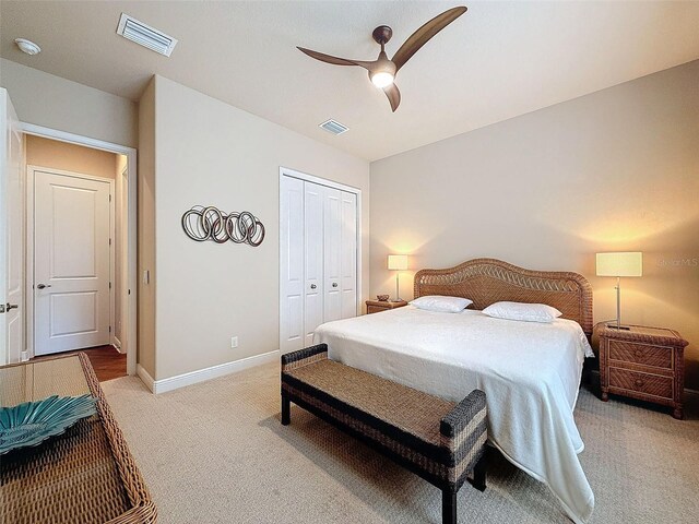 bedroom featuring ceiling fan, light carpet, and a closet