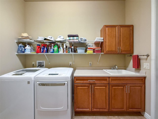 laundry area featuring washing machine and clothes dryer, sink, and cabinets