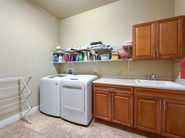 washroom featuring a textured ceiling, washer and dryer, cabinets, and sink