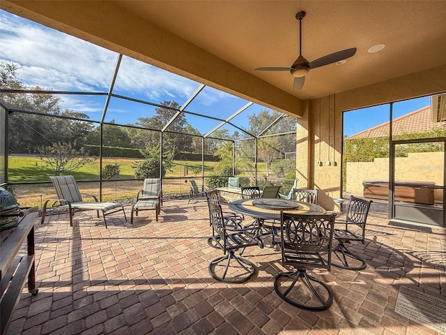 view of patio / terrace with glass enclosure, a hot tub, and ceiling fan