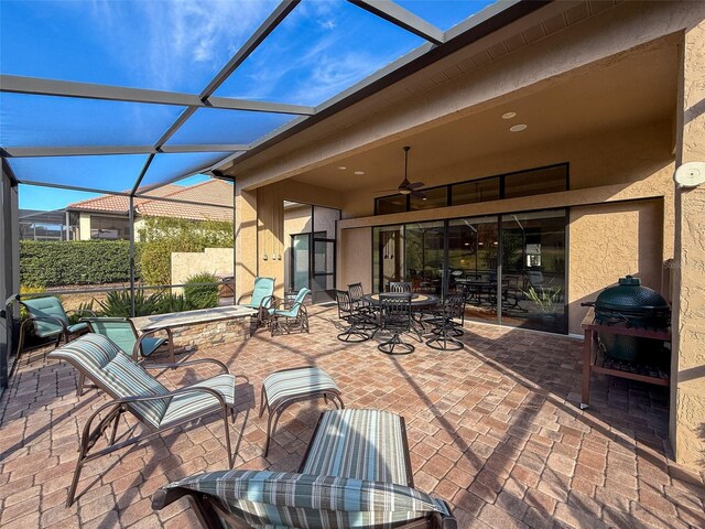 view of patio with ceiling fan and glass enclosure