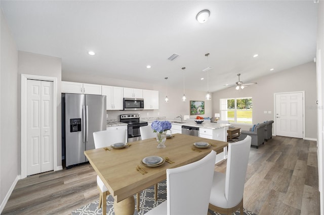 dining space with ceiling fan, lofted ceiling, sink, and light hardwood / wood-style flooring