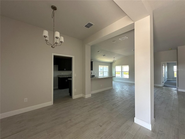 spare room featuring wood-type flooring, vaulted ceiling, and a notable chandelier