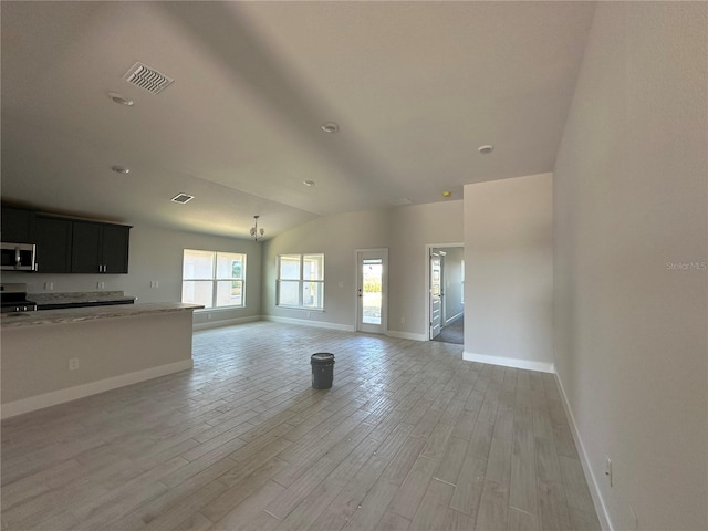 unfurnished living room featuring an inviting chandelier, lofted ceiling, and light hardwood / wood-style flooring