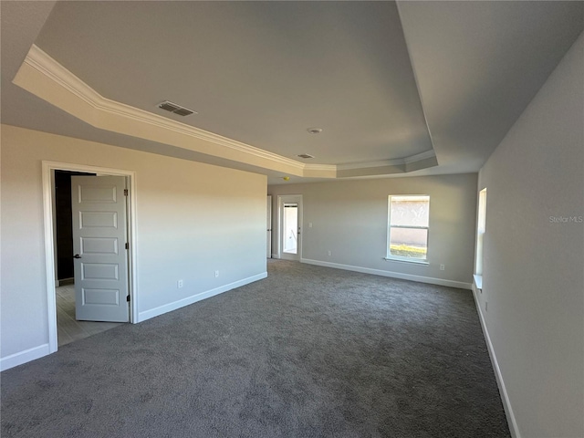 unfurnished room featuring dark carpet, a raised ceiling, and ornamental molding