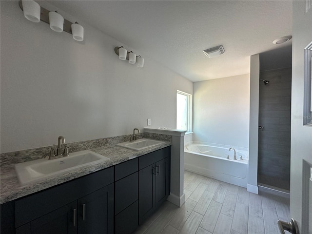 bathroom with hardwood / wood-style flooring, vanity, separate shower and tub, and a textured ceiling