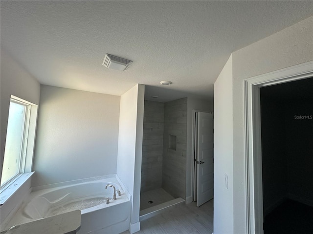 bathroom featuring plus walk in shower, hardwood / wood-style floors, and a textured ceiling