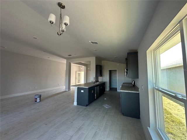 kitchen with lofted ceiling, light hardwood / wood-style floors, a notable chandelier, and sink