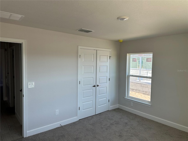 unfurnished bedroom with a closet, dark carpet, and a textured ceiling