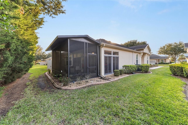 rear view of house featuring a sunroom and a lawn