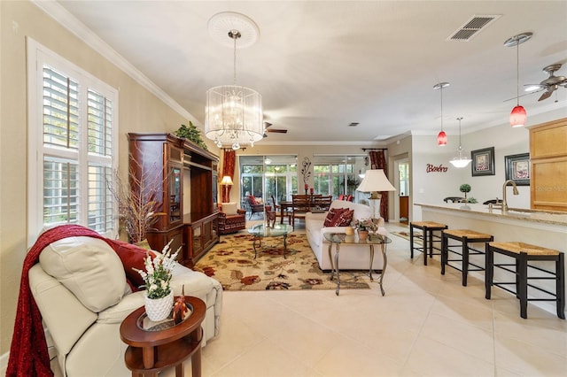 tiled living room with ceiling fan with notable chandelier and ornamental molding