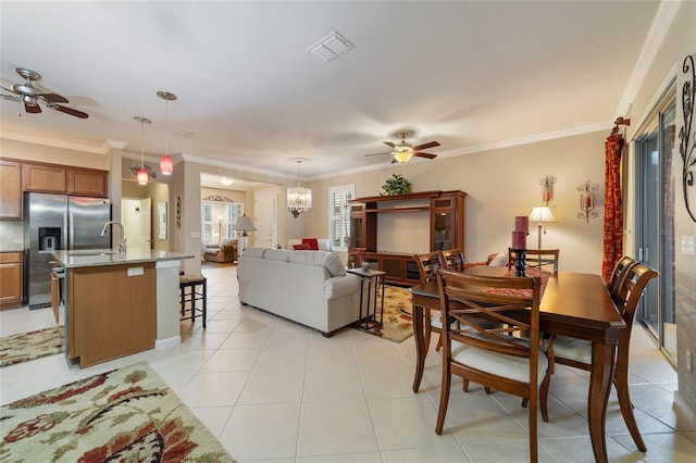 tiled dining area with ceiling fan with notable chandelier, ornamental molding, and sink