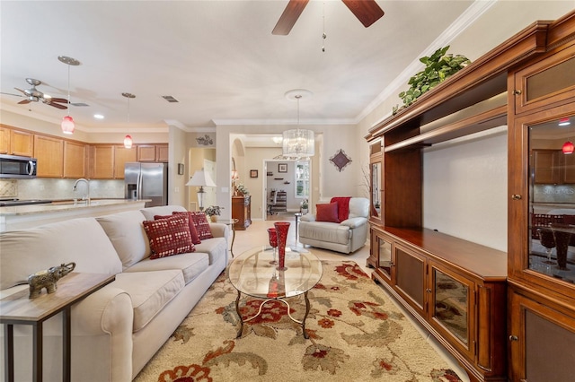 living room featuring ceiling fan with notable chandelier, sink, and crown molding