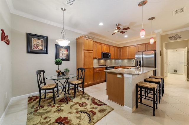 kitchen with light stone countertops, backsplash, stainless steel appliances, a kitchen island with sink, and sink