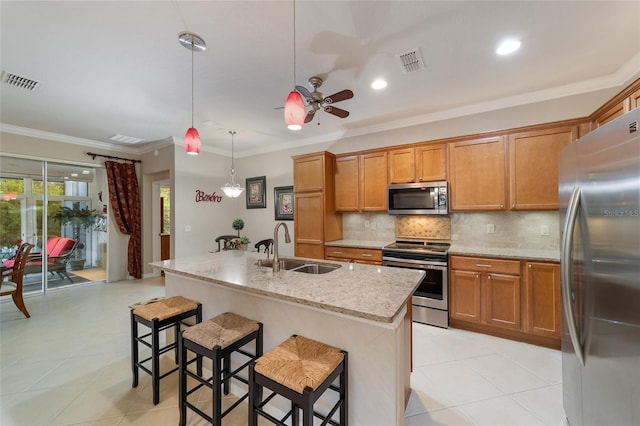 kitchen featuring appliances with stainless steel finishes, light stone counters, sink, a center island with sink, and hanging light fixtures