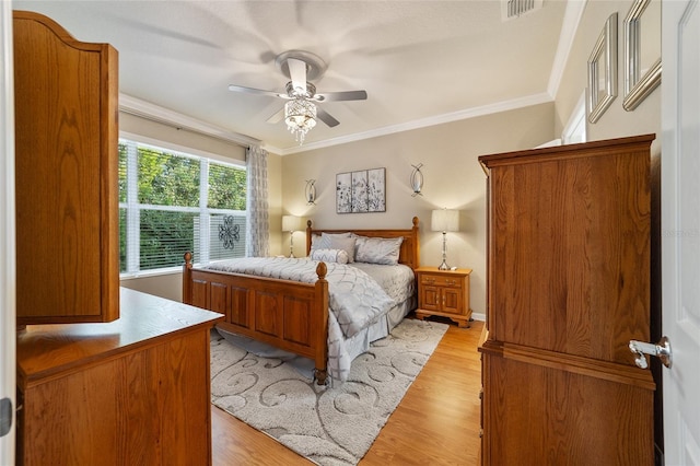 bedroom with light hardwood / wood-style flooring, ceiling fan, and ornamental molding