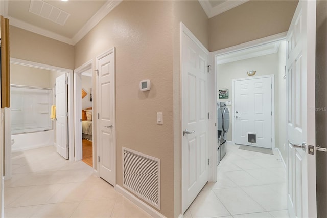 hall with separate washer and dryer, light tile patterned flooring, and ornamental molding