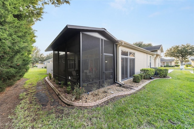 view of side of home with a lawn and a sunroom