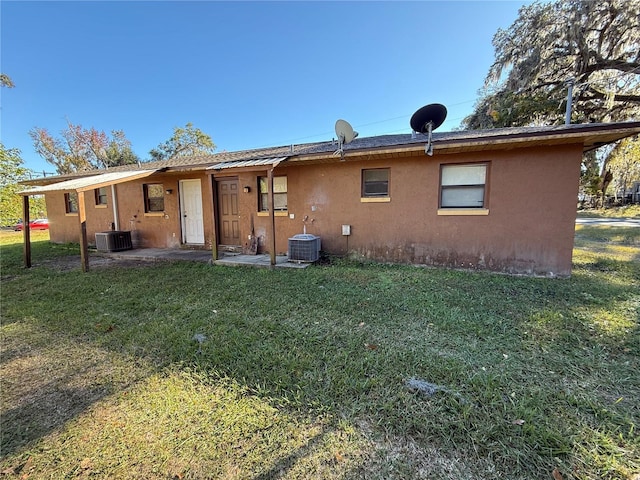 back of property featuring central AC unit and a yard