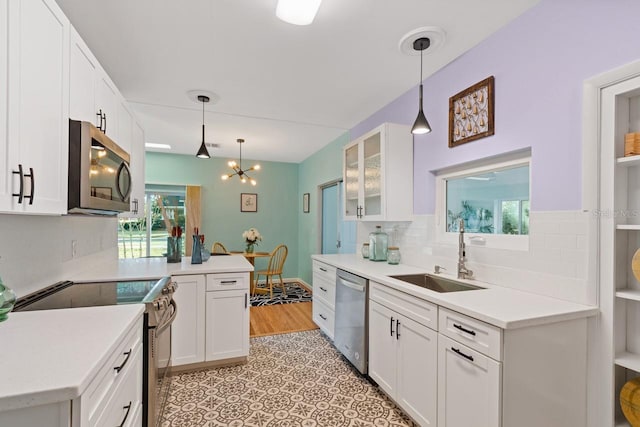 kitchen with white cabinetry, sink, backsplash, decorative light fixtures, and appliances with stainless steel finishes