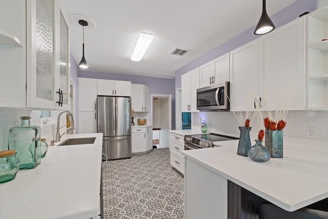 kitchen with kitchen peninsula, white cabinets, stainless steel appliances, and decorative light fixtures