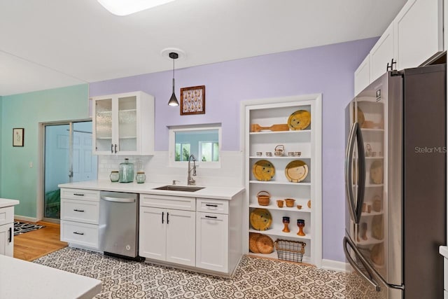 kitchen featuring decorative light fixtures, stainless steel appliances, white cabinetry, and sink