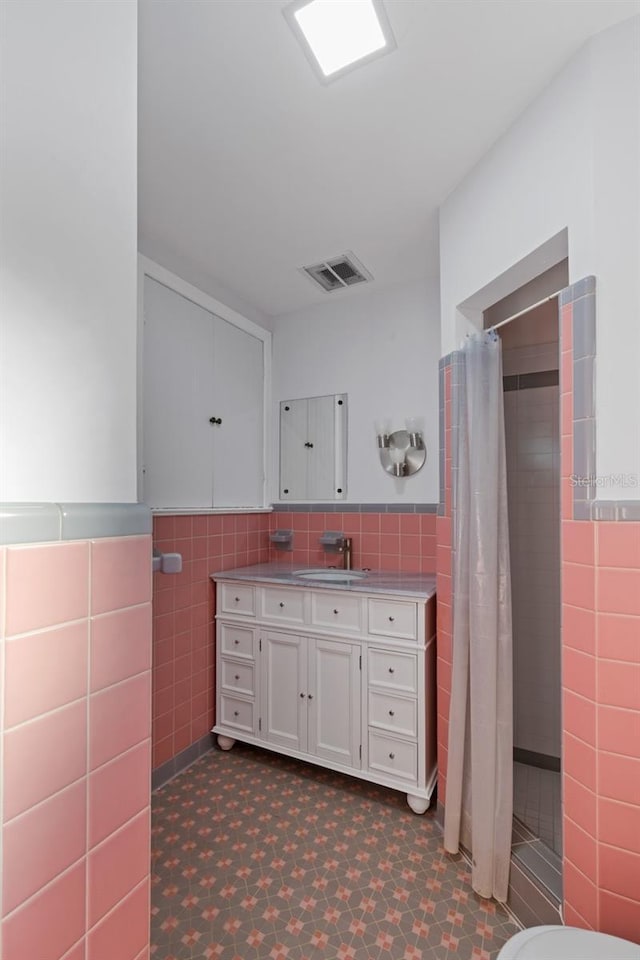 bathroom with vanity, curtained shower, and tile walls