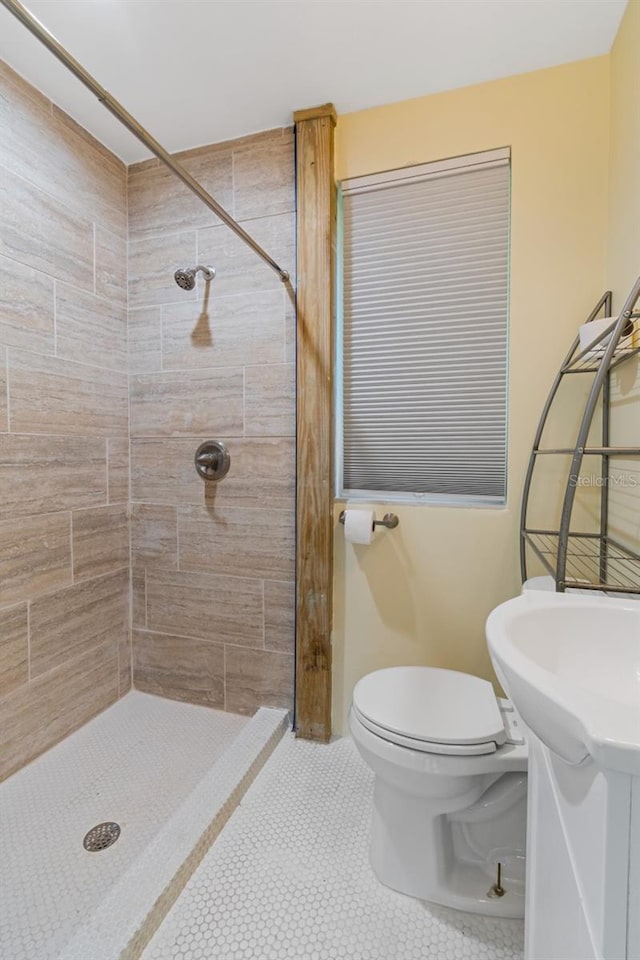 bathroom featuring tile patterned flooring, vanity, toilet, and a tile shower