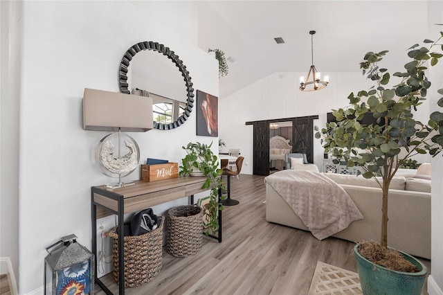 bedroom featuring light hardwood / wood-style flooring, high vaulted ceiling, and an inviting chandelier