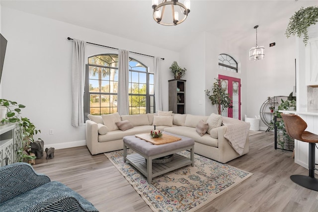 living room featuring light hardwood / wood-style floors, french doors, and an inviting chandelier