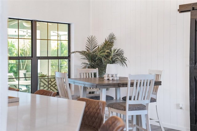 dining area with a barn door and wooden walls