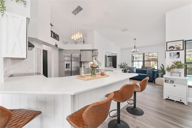 kitchen with a kitchen bar, kitchen peninsula, stainless steel fridge, and decorative backsplash