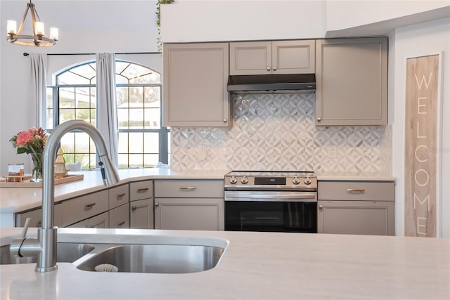 kitchen with backsplash, stainless steel electric stove, sink, hanging light fixtures, and gray cabinets