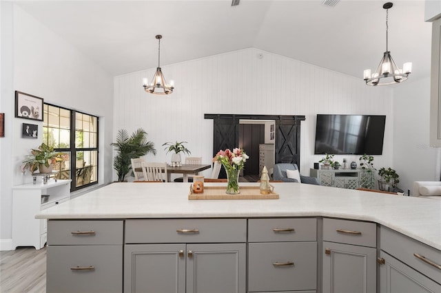 kitchen with gray cabinetry, vaulted ceiling, light hardwood / wood-style flooring, a notable chandelier, and hanging light fixtures