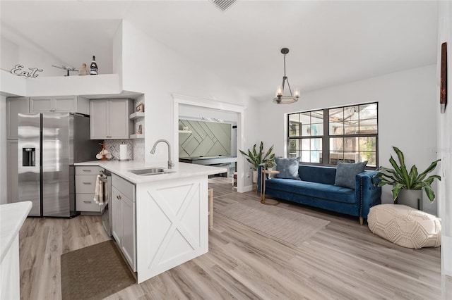 kitchen featuring appliances with stainless steel finishes, gray cabinetry, sink, pendant lighting, and light hardwood / wood-style flooring