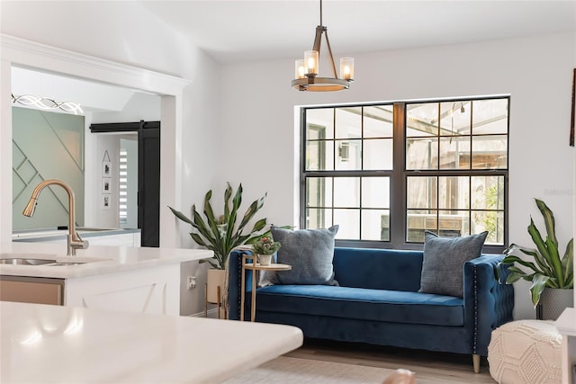 living area featuring hardwood / wood-style floors, a barn door, a notable chandelier, and sink