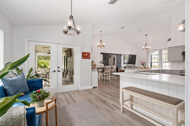 kitchen with light hardwood / wood-style flooring, lofted ceiling, sink, and french doors