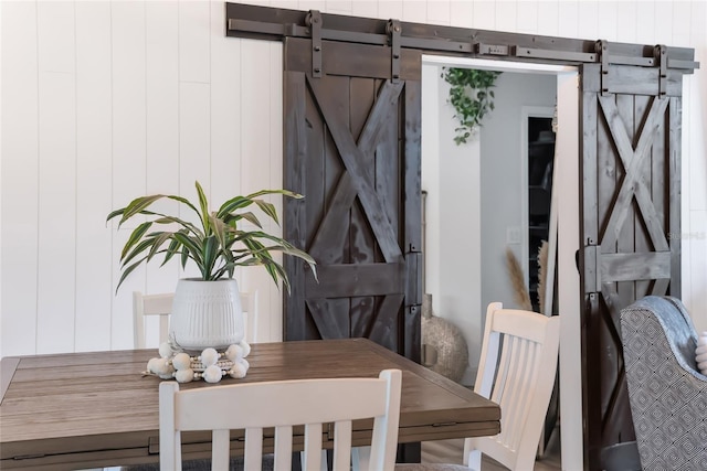 dining space with a barn door and wooden walls