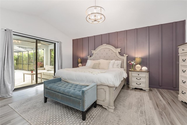 bedroom featuring access to outside, an inviting chandelier, lofted ceiling, and light wood-type flooring