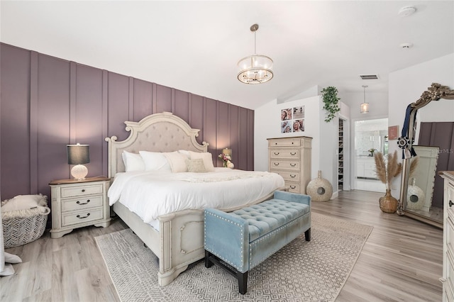 bedroom featuring a notable chandelier, lofted ceiling, and light wood-type flooring