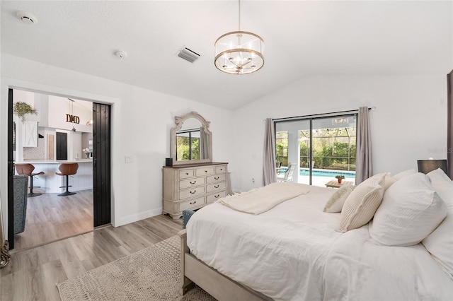 bedroom with a notable chandelier, access to exterior, lofted ceiling, and light hardwood / wood-style flooring