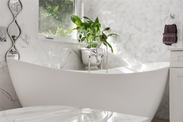 bathroom with a tub to relax in and tile walls