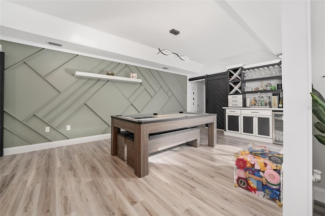 game room with bar, a barn door, hardwood / wood-style floors, and beverage cooler