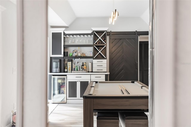 bar with pendant lighting, light hardwood / wood-style floors, beverage cooler, and lofted ceiling