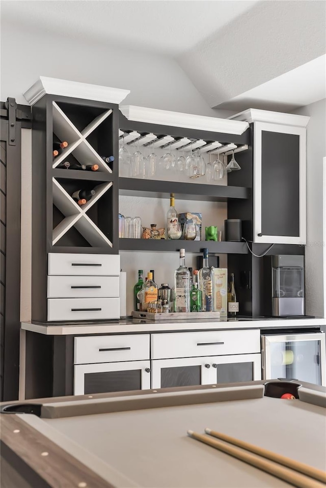 bar featuring white cabinetry and lofted ceiling