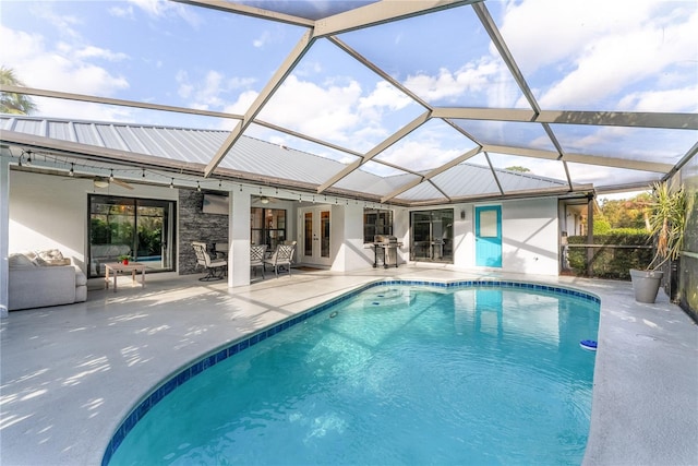 view of pool with ceiling fan, a patio area, glass enclosure, and french doors