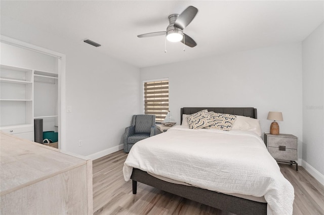 bedroom featuring a walk in closet, ceiling fan, and light wood-type flooring