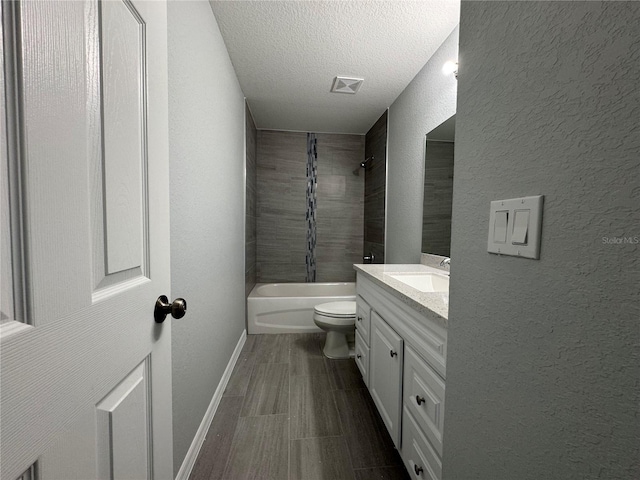 full bathroom featuring tiled shower / bath combo, toilet, a textured ceiling, and vanity