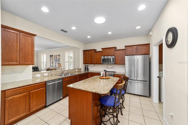 kitchen with kitchen peninsula, a kitchen breakfast bar, ornamental molding, stainless steel appliances, and light tile patterned floors