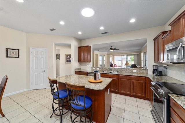 kitchen featuring sink, stainless steel appliances, tasteful backsplash, kitchen peninsula, and a breakfast bar area